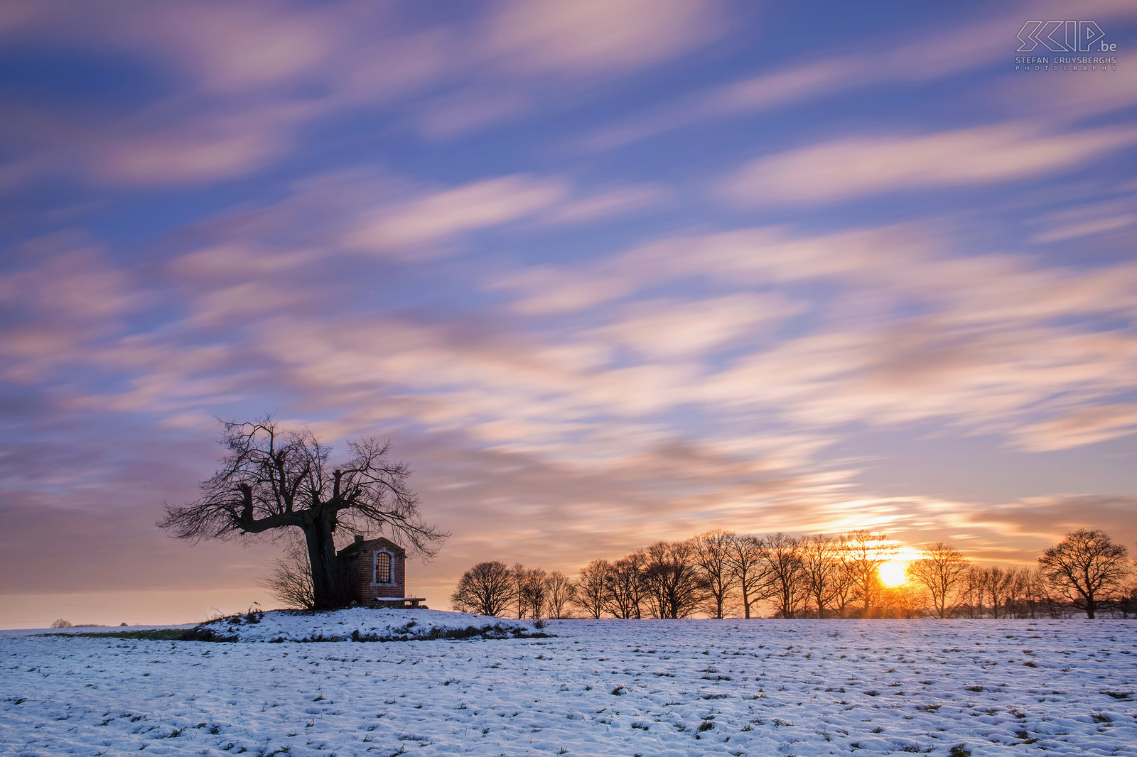 Winter in Sint-Pieters-Rode - Sunset at the chapel The small chapel of Saint Joseph is located in a field under an old linden tree nearby the castle of Horst (Sint-Pieters-Rode, Belgium). It has been built in the beginning of the 19th century. This long exposure shot is made a sunset.<br />
 Stefan Cruysberghs